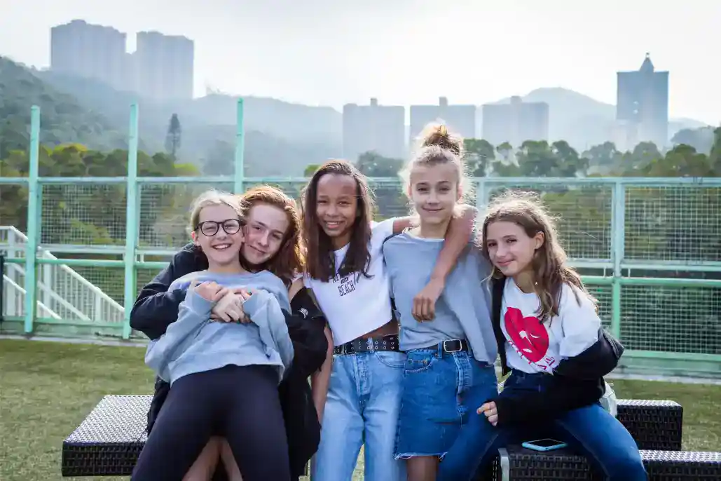 Diverso grupo de entusiastas estudiantes sonriendo al aire libre en el campus de una escuela internacional.