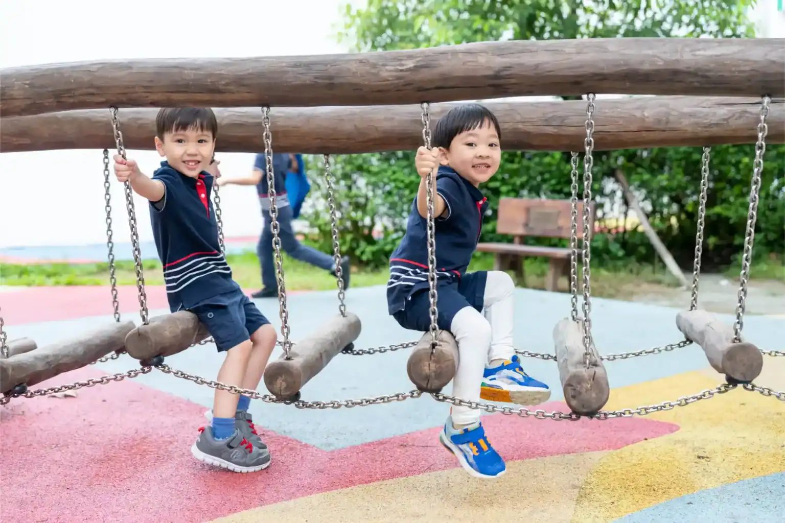 Alegres niños juegan en un puente de aventura de madera en un parque infantil de los Colegios del Mundo, que promueve el aprendizaje activo y la educación al aire libre.