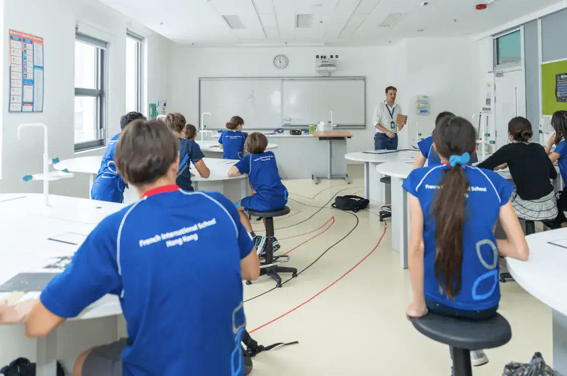 Innovadora aula de ciencias con alumnos y profesor en los Colegios del Mundo de Hong Kong, fomentando la educación STEM.