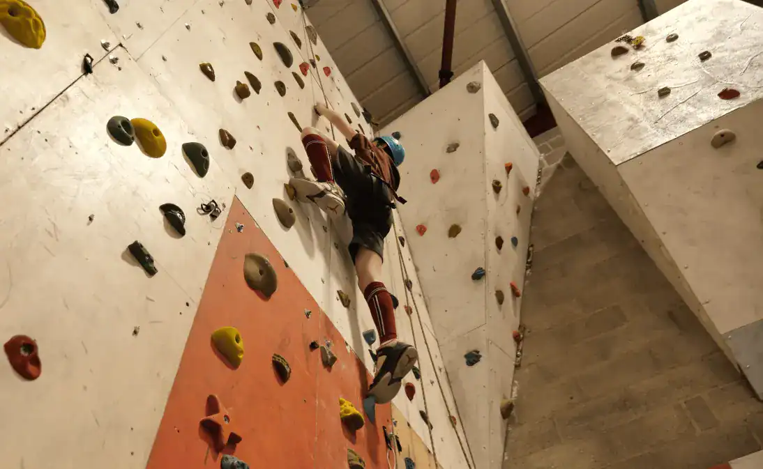 Arrampicatore sulla parete di roccia interna di una struttura sportiva scolastica mondiale, che promuove l'educazione fisica e l'apprendimento dell'avventura.