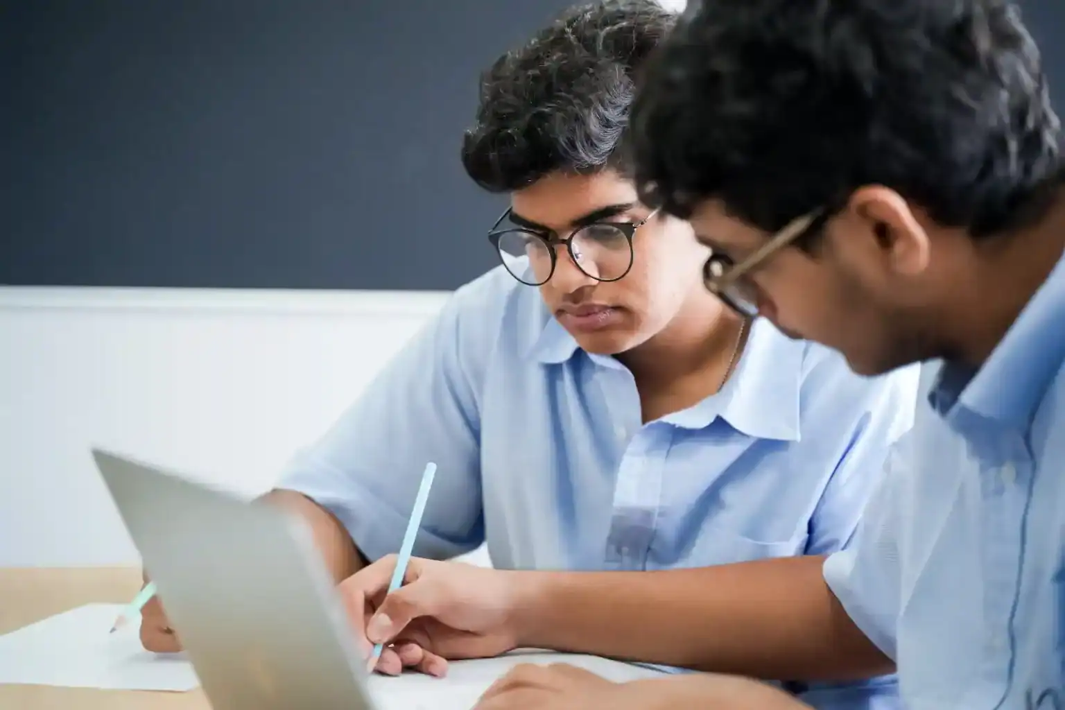 Focused students studying with a tablet and notebooks at World Schools, emphasizing quality education and academic excellence.