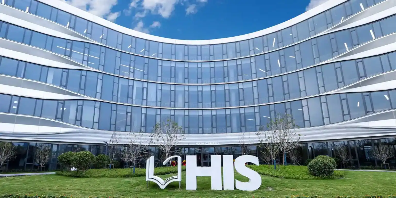 Bright modern school building with glass facade and green lawn, inspired by world-class international education.