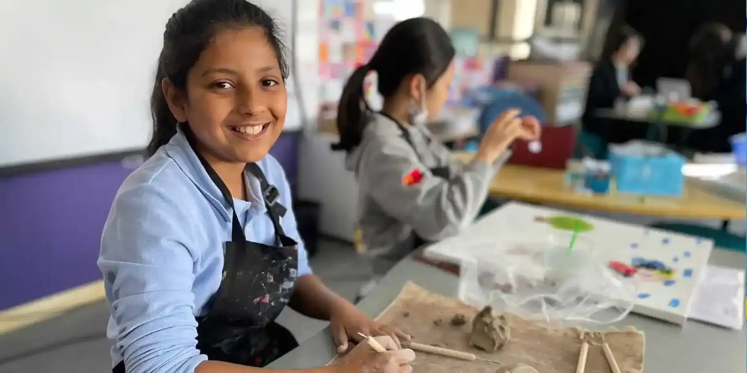 Young girl engaging in arts and crafts in a classroom, part of a global school environment.