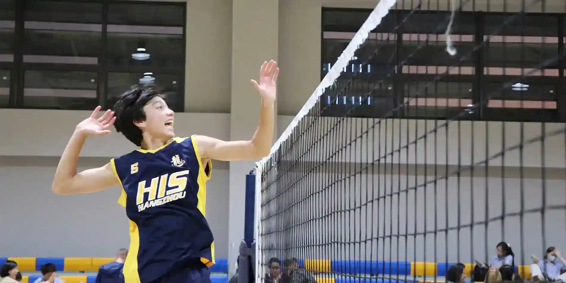 Young female volleyball player jumping to block the ball at school sports event.