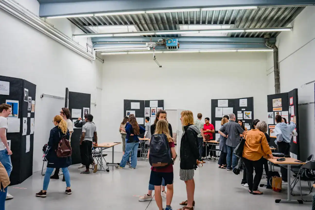 High school students attending an educational exhibition at a modern facility with display boards showcasing academic projects and information.