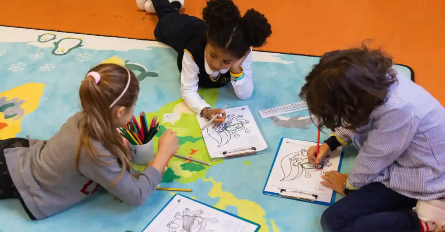 Kinder zeichnen und malen auf einer Weltkarte, um das globale Lernen an Weltschulen zu fördern.