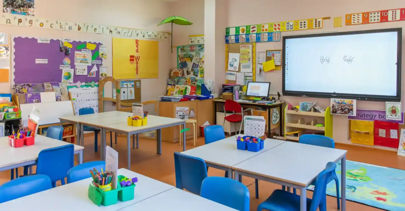 Helles, farbenfrohes Klassenzimmer in einer Weltschule mit Schreibtischen, Lernplakaten und interaktiven Lernmitteln.