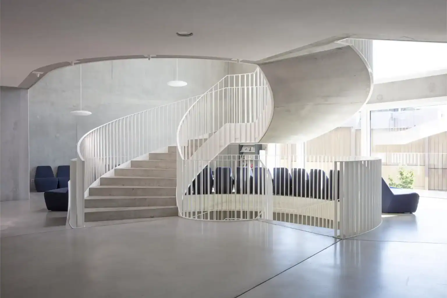 Spacious modern interior of a contemporary school building with spiral staircase and seating area.