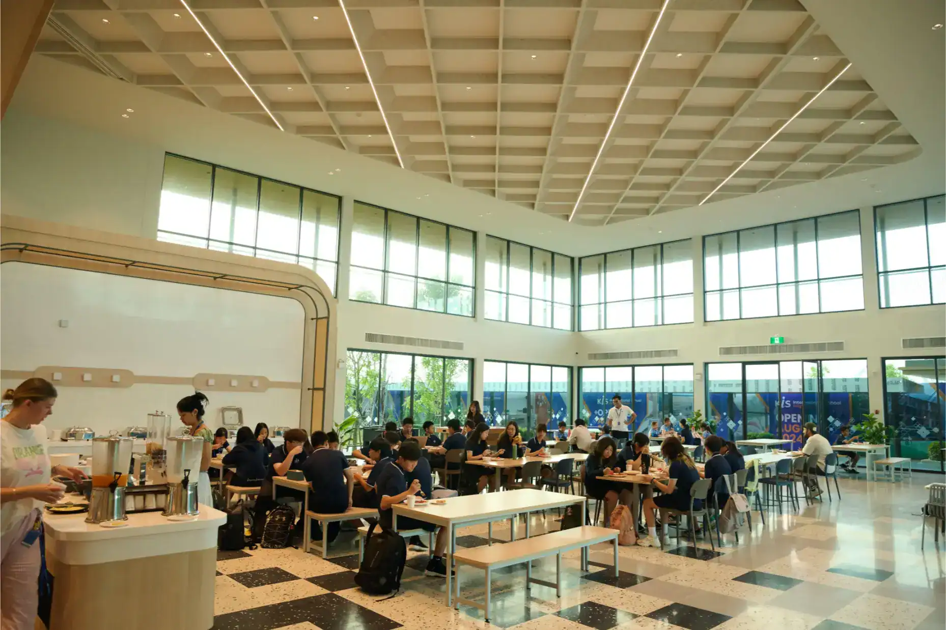 Modern international school cafeteria with students, bright natural lighting, and spacious design.