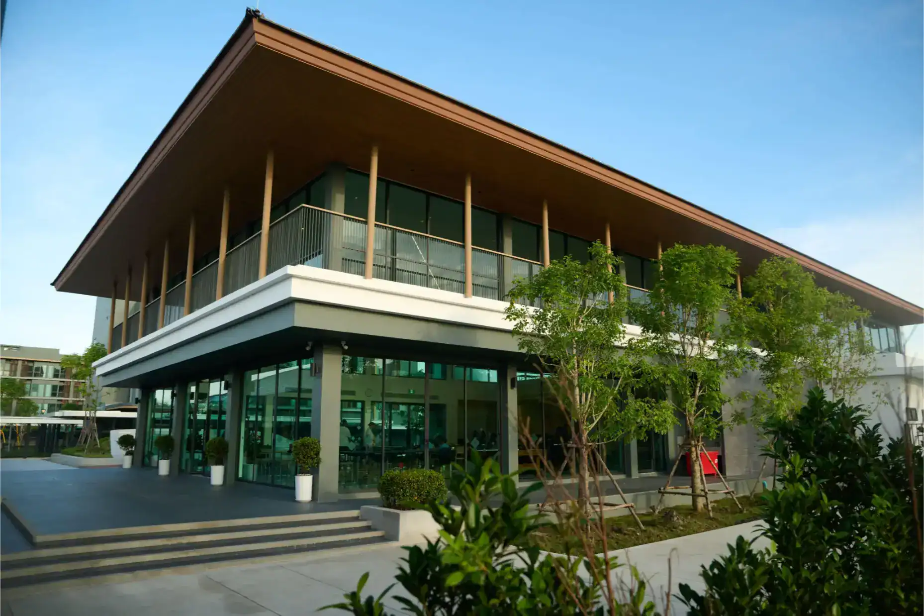 Modern international school building with glass walls and greenery, focusing on global education and excellence.