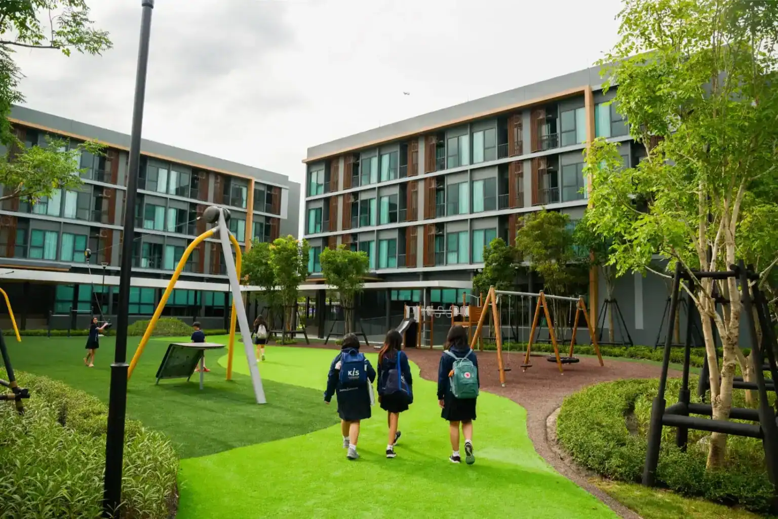 Modern school campus with outdoor play area and students walking to class.