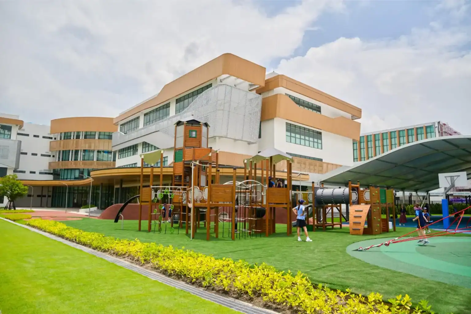 Bright modern school building with outdoor playground and green lawn, ideal for student learning and recreation.