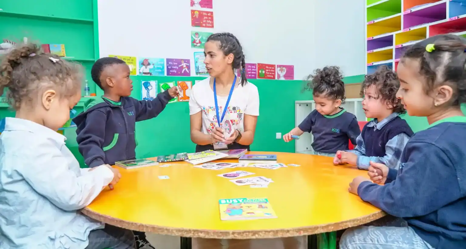 Brightly lit classroom with diverse young students engaging with a teacher during educational activity.