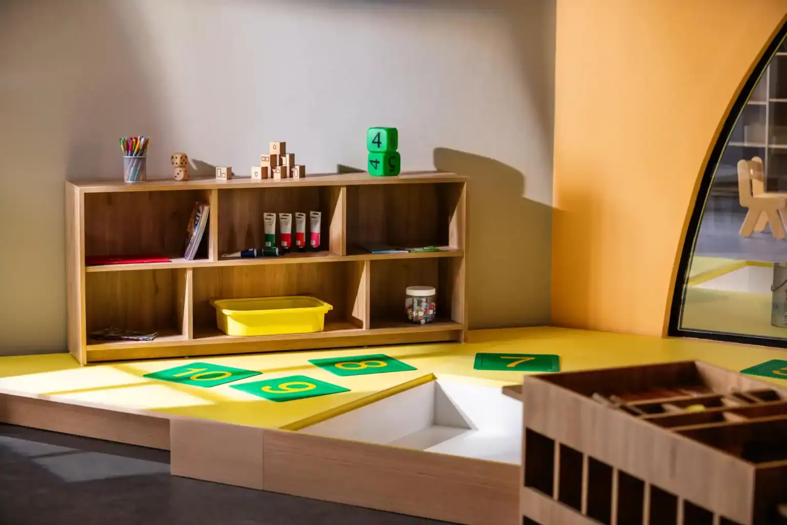 Colorful wooden educational toys and labeled mats in a modern classroom setting.