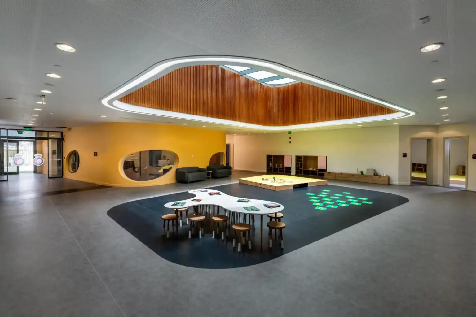 Bright modern school lobby with interactive play area for children, vibrant colors, and innovative design.