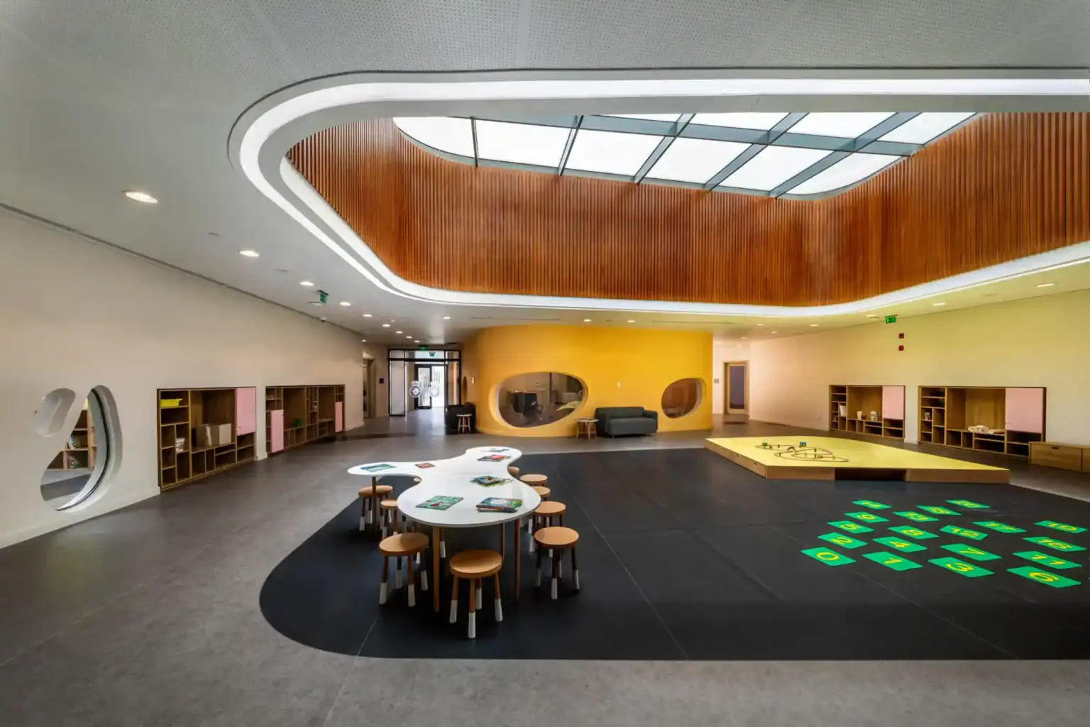 Bright modern school interior with flexible learning spaces, colorful design, and play areas for children.