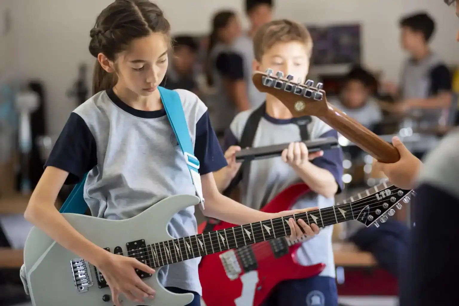 多様で革新的な芸術プログラムを提供するワールド・スクールで、音楽の授業でエレキギターを演奏する生徒たち。.