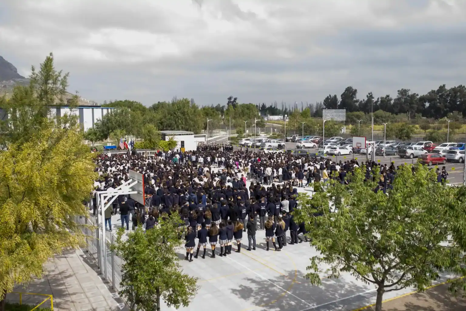 屋外キャンパスで行われたワールドスクールのイベントで、学校のバスケットボールコートに集まった生徒たち。.