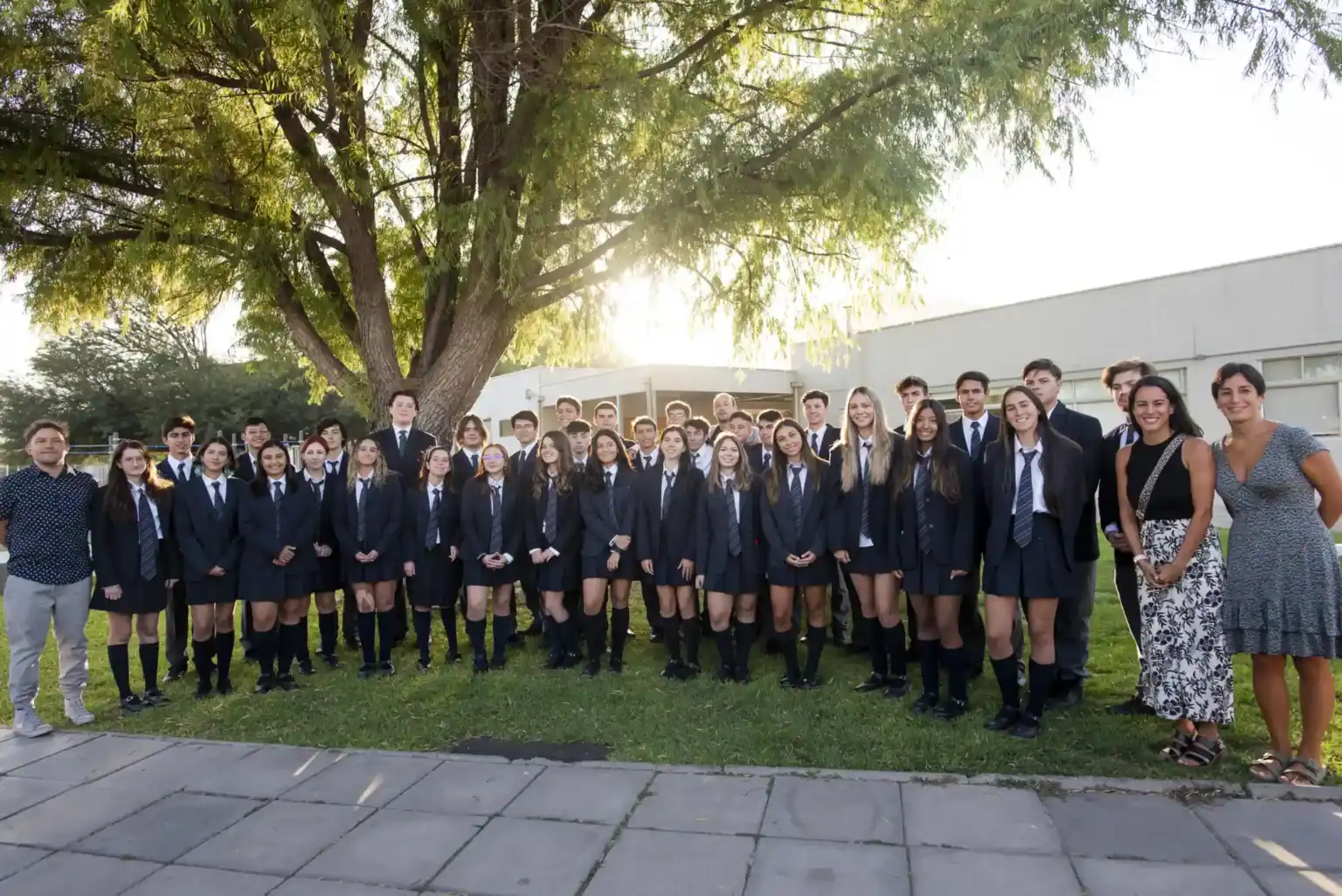 グローバル教育と多様性を受け入れるワールドスクールの屋外キャンパスで、制服を着た生徒たち。.