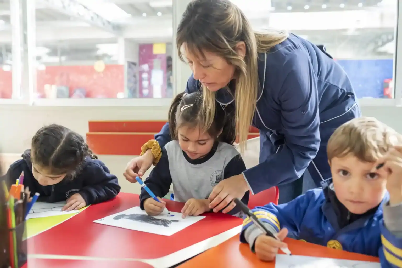 美術の授業で幼い生徒を指導する、きめ細かな教師の幼児教育。.