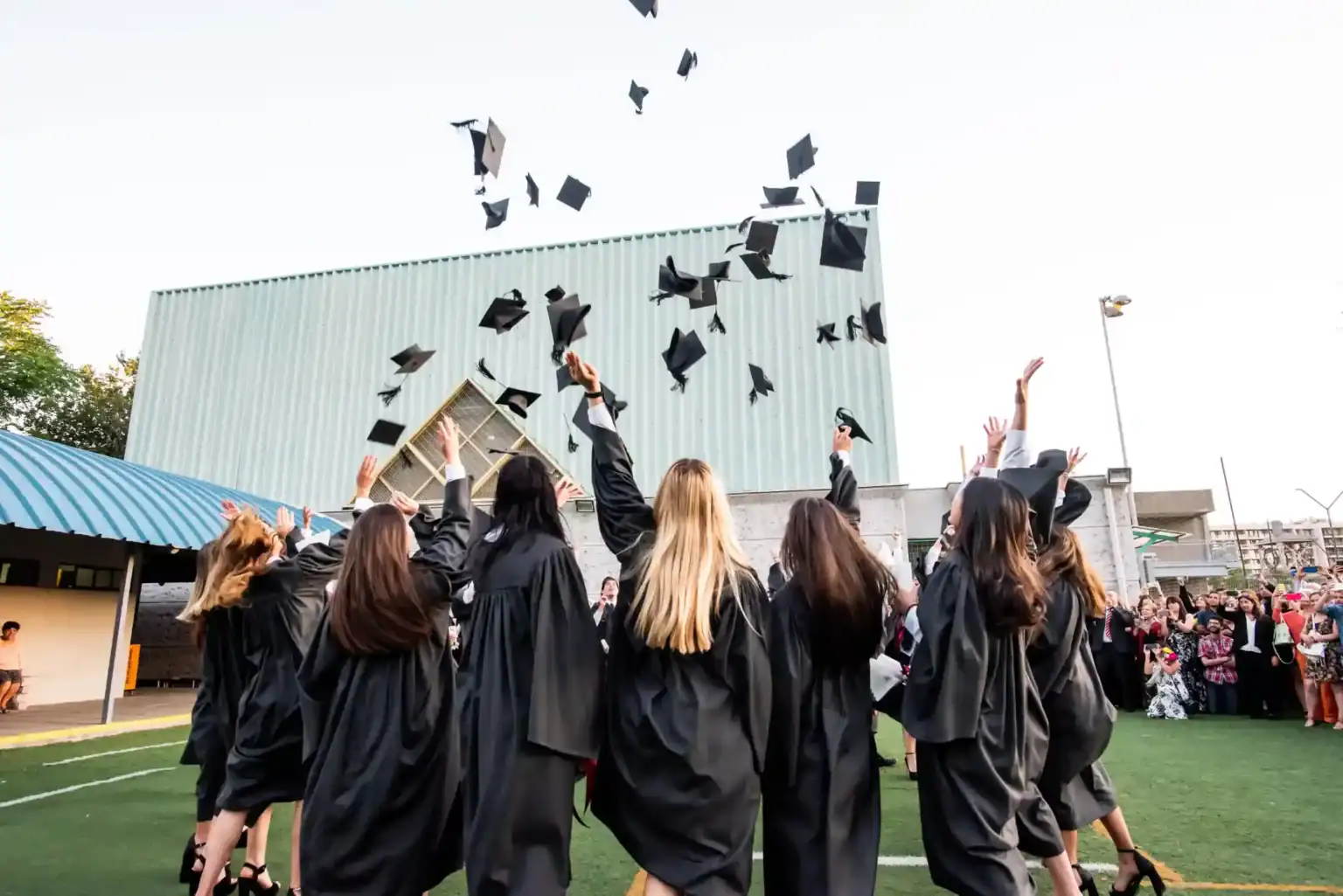 ワールドスクールの卒業式で、帽子を空中に投げて祝う卒業生たち。.