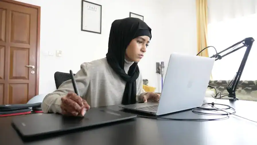 Focused female student studying online at home, using a laptop for distance learning at a world school.