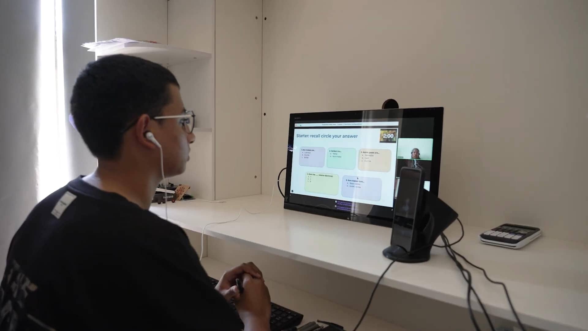 Student participating in online learning at a modern classroom with digital tools.