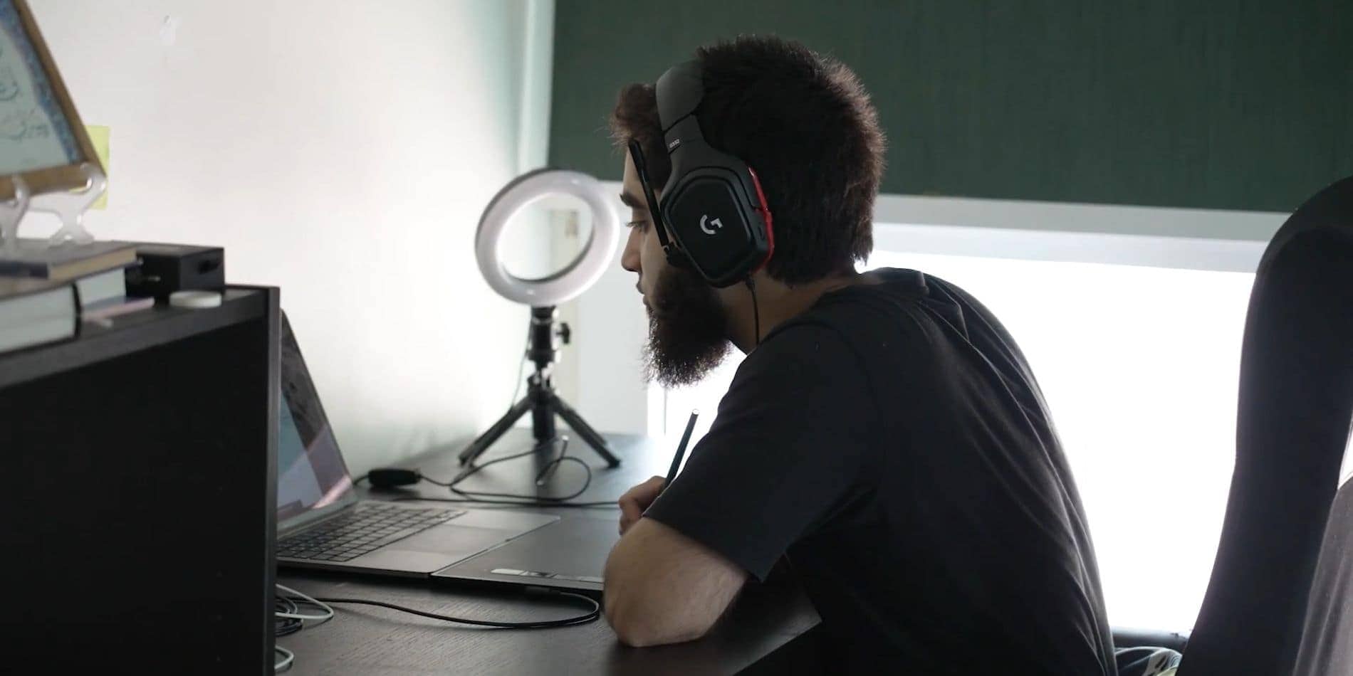 Focused student wearing gaming headset working on laptop at school.