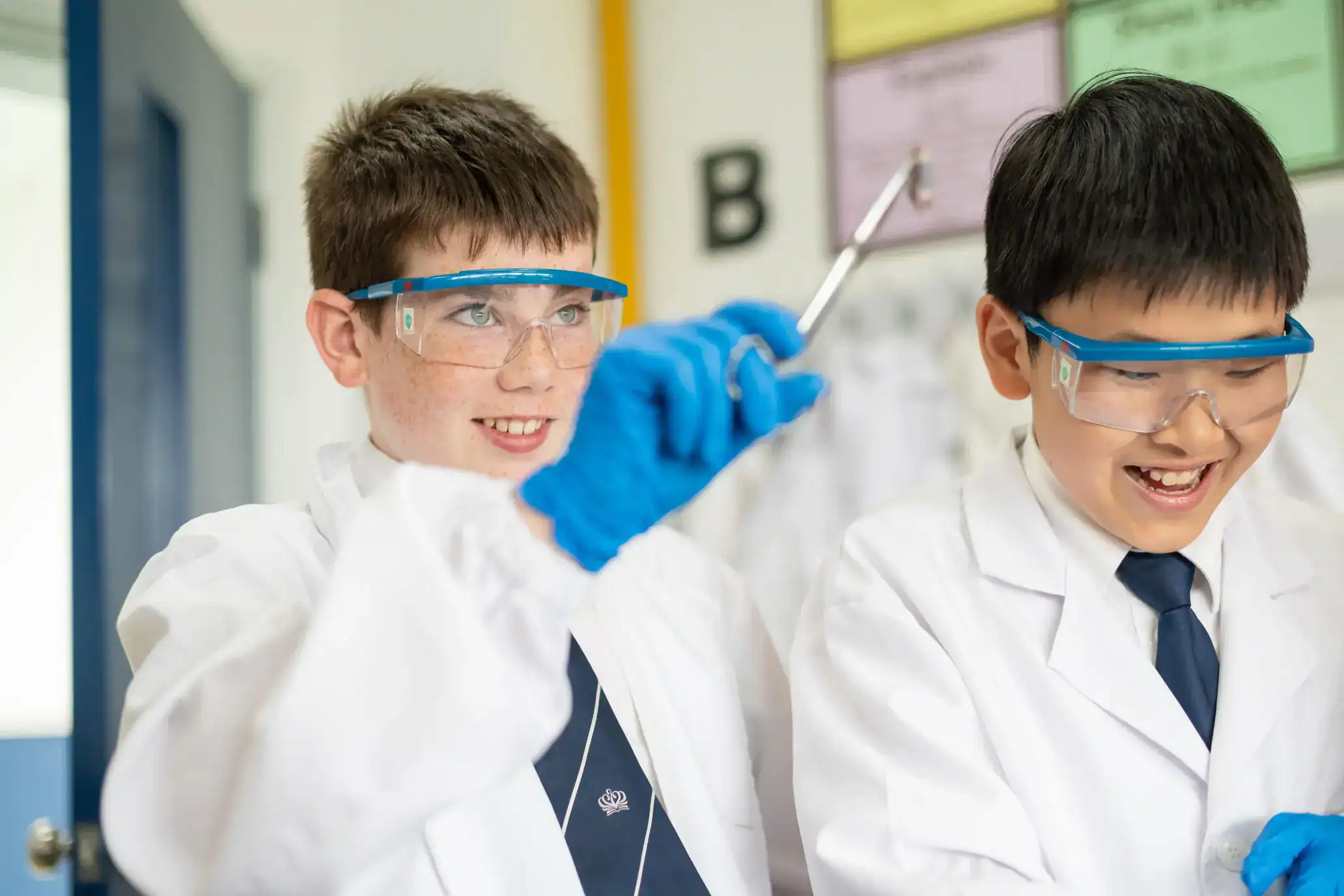 1. Boys wearing safety goggles conducting science experiment in classroom.