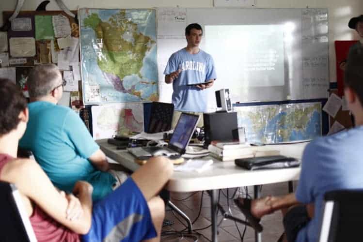 Smart classroom with diverse students, world maps, and digital tools, promoting global education excellence.