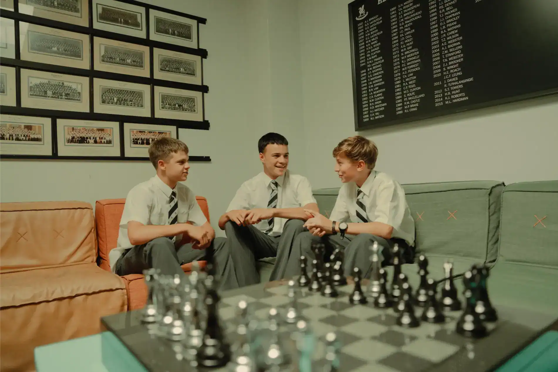 Young students playing chess and having engaging conversations in a school lounge.