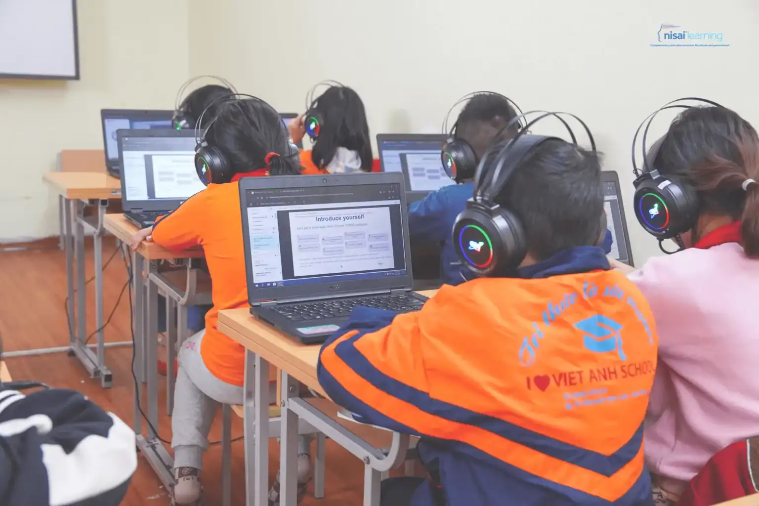 Studenci informatyki w klasie, uczący się umiejętności cyfrowych z laptopami i słuchawkami.