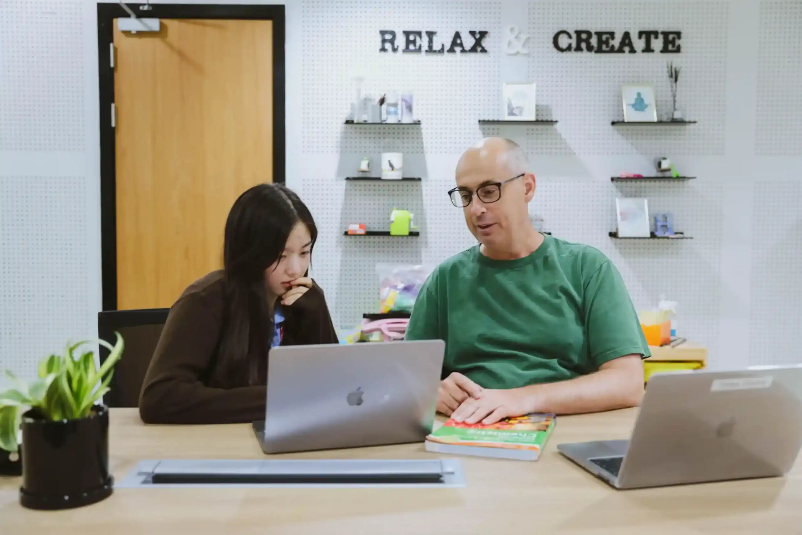 Focused student and teacher collaborating at a modern classroom desk with laptops, promoting innovative learning at world schools.