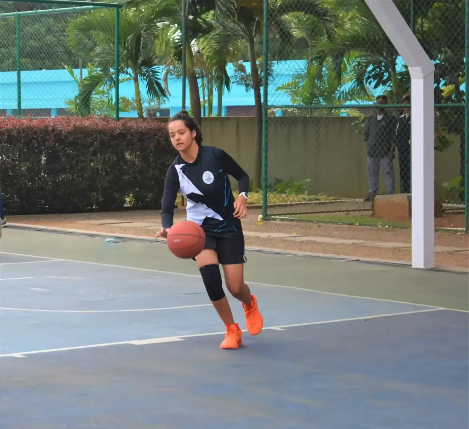 Young female student playing basketball on an outdoor court at World Schools.