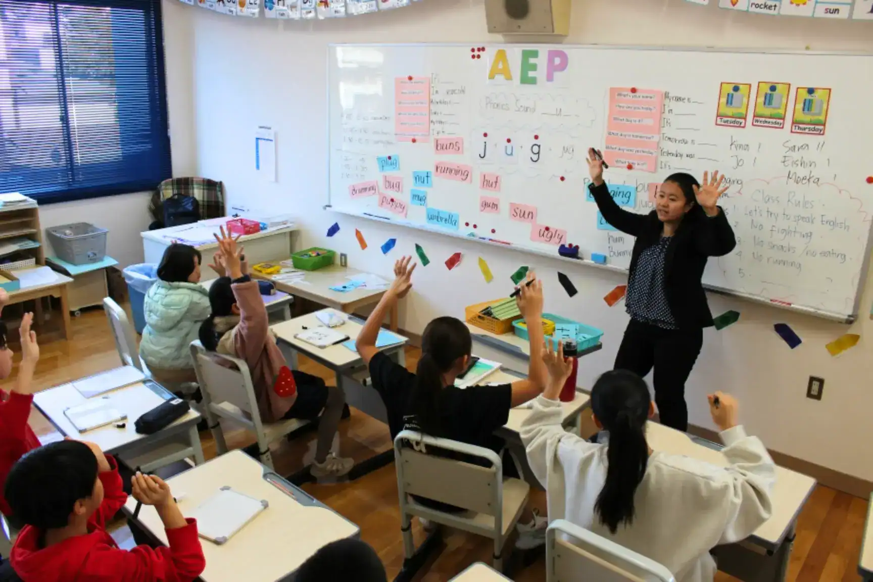 Bright classroom with students raising hands during English lesson at a World Schools educational institution.