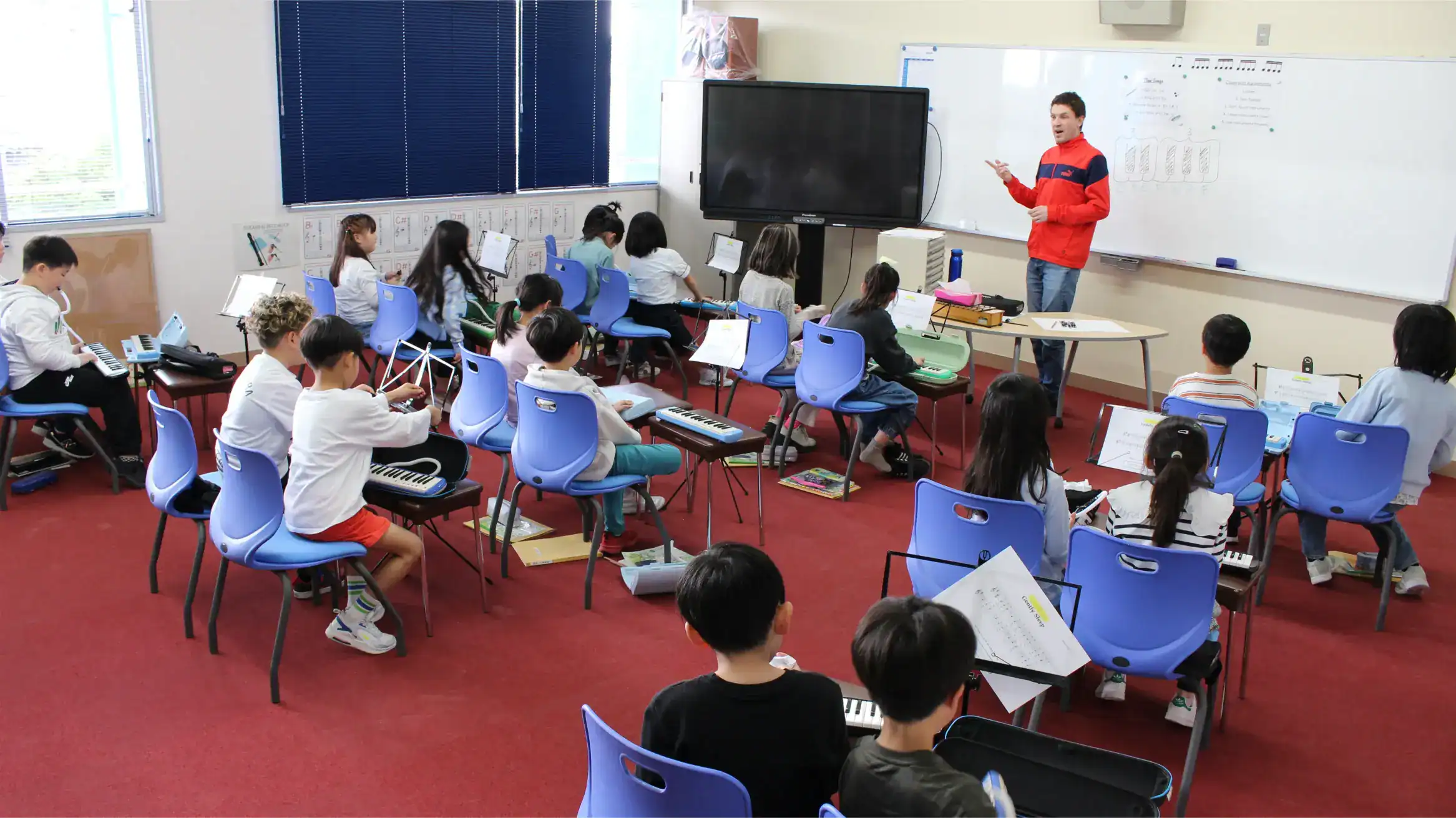 Innovative music classroom at a world school with students learning instruments and a teacher conducting a lesson.