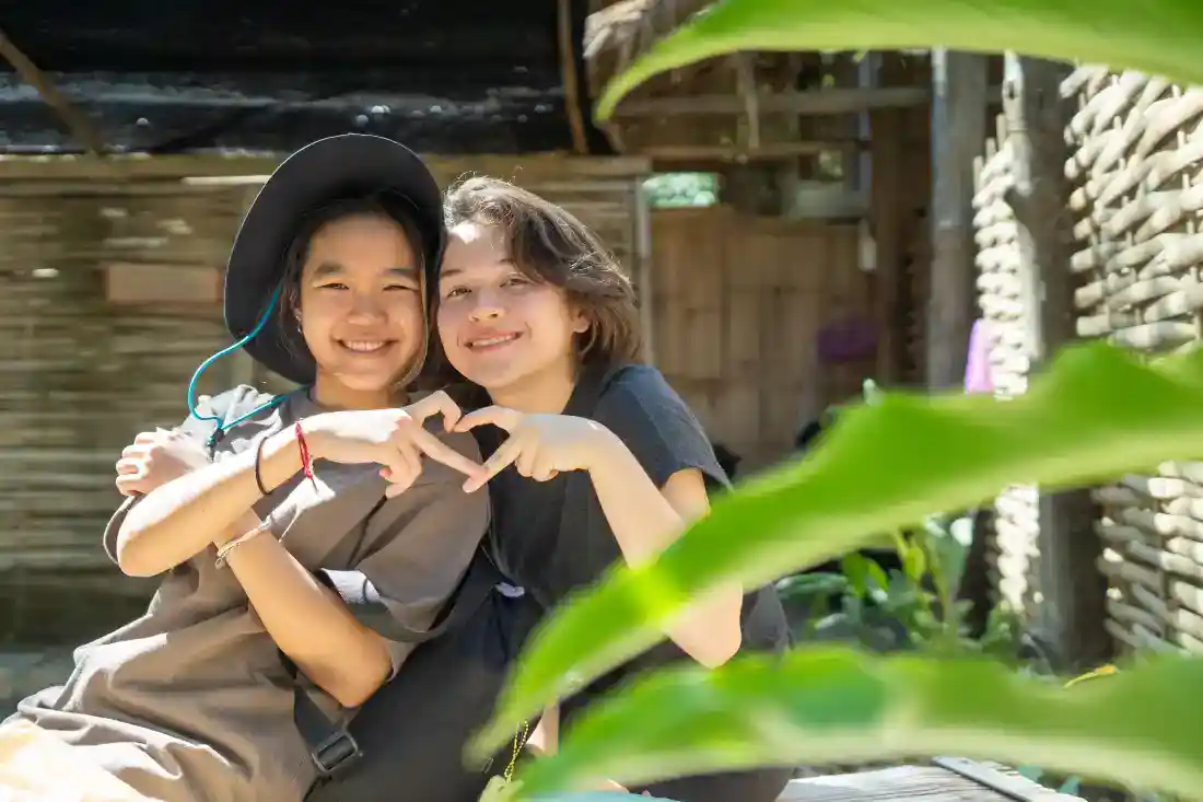 Happy children making a heart shape with their hands outdoors at World Schools.