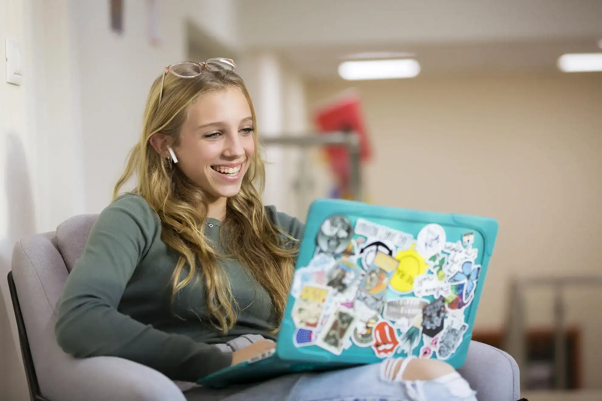 Young girl using a laptop with stickers, studying at World Schools for a global education experience.