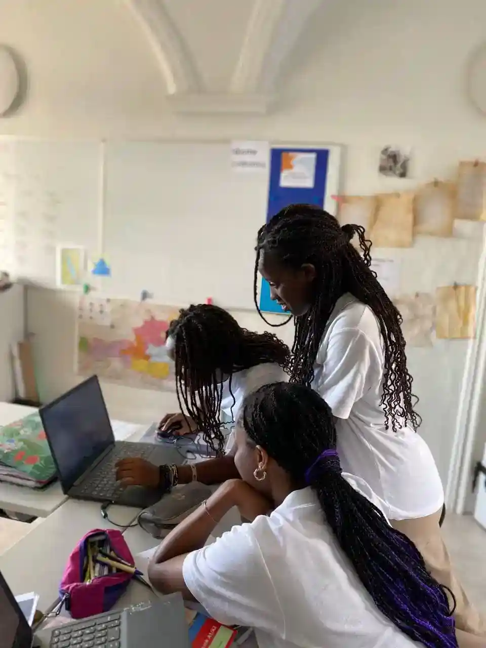 Smart African girls collaborating on a laptop in a classroom, emphasizing global education and diversity at World Schools.