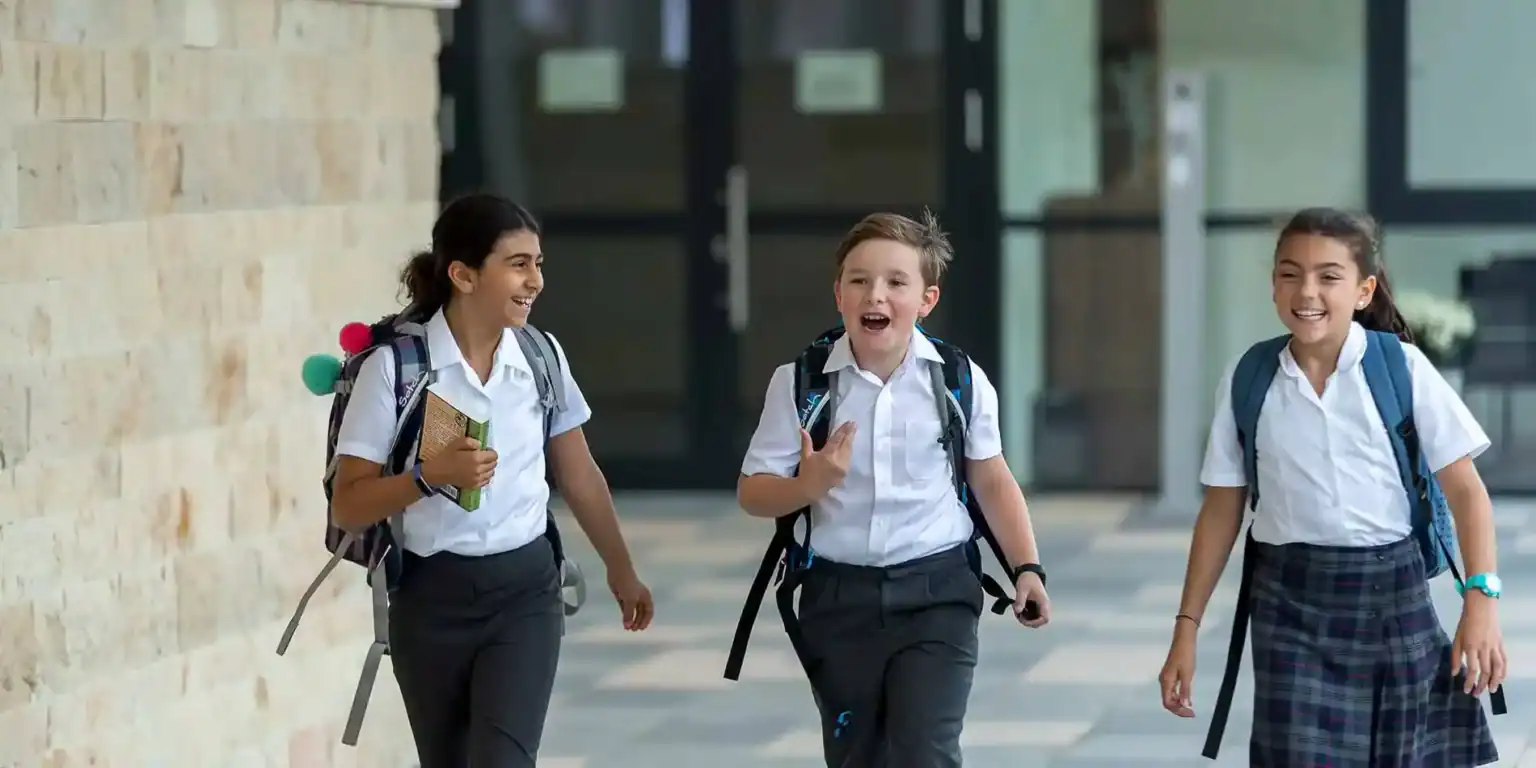 Happy diverse school children walking outside with backpacks, smiling, embracing education.