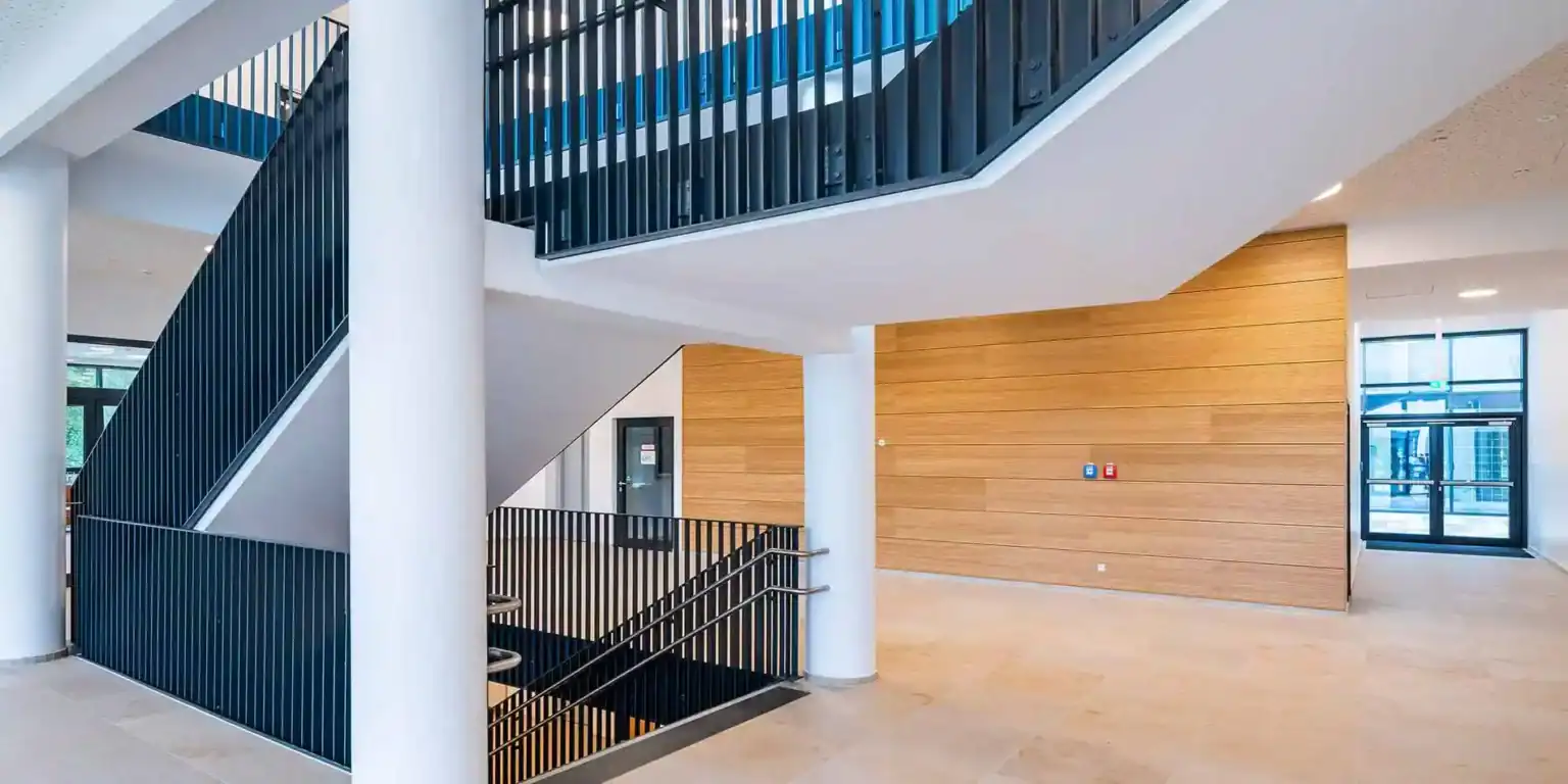 Modern school interior with staircase and wooden walls, bright open design for innovative learning environments.