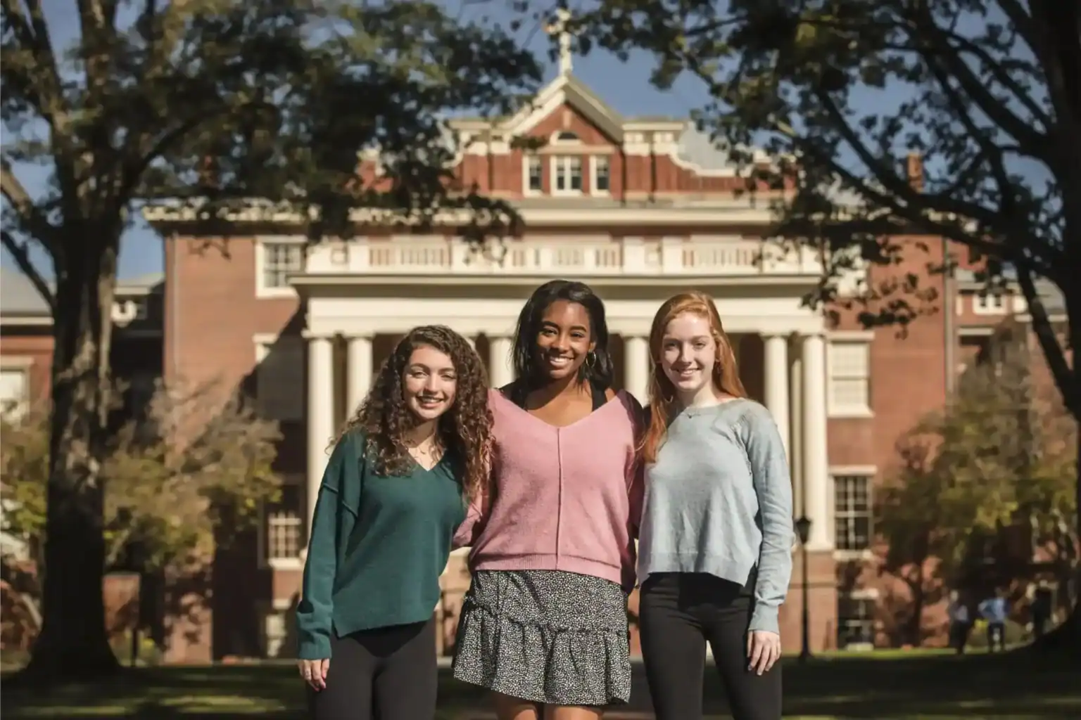 Diverse students smiling outdoors in front of a historic school building, promoting international education and global school networks.