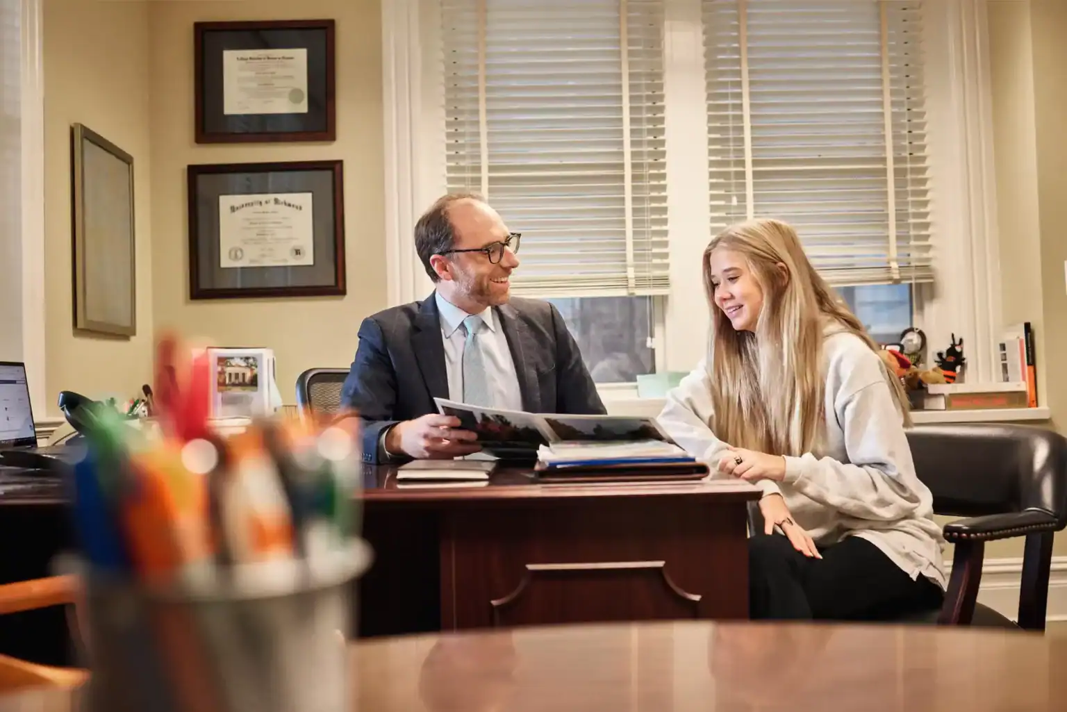 Friendly school counselor discussing academic success with student in office.