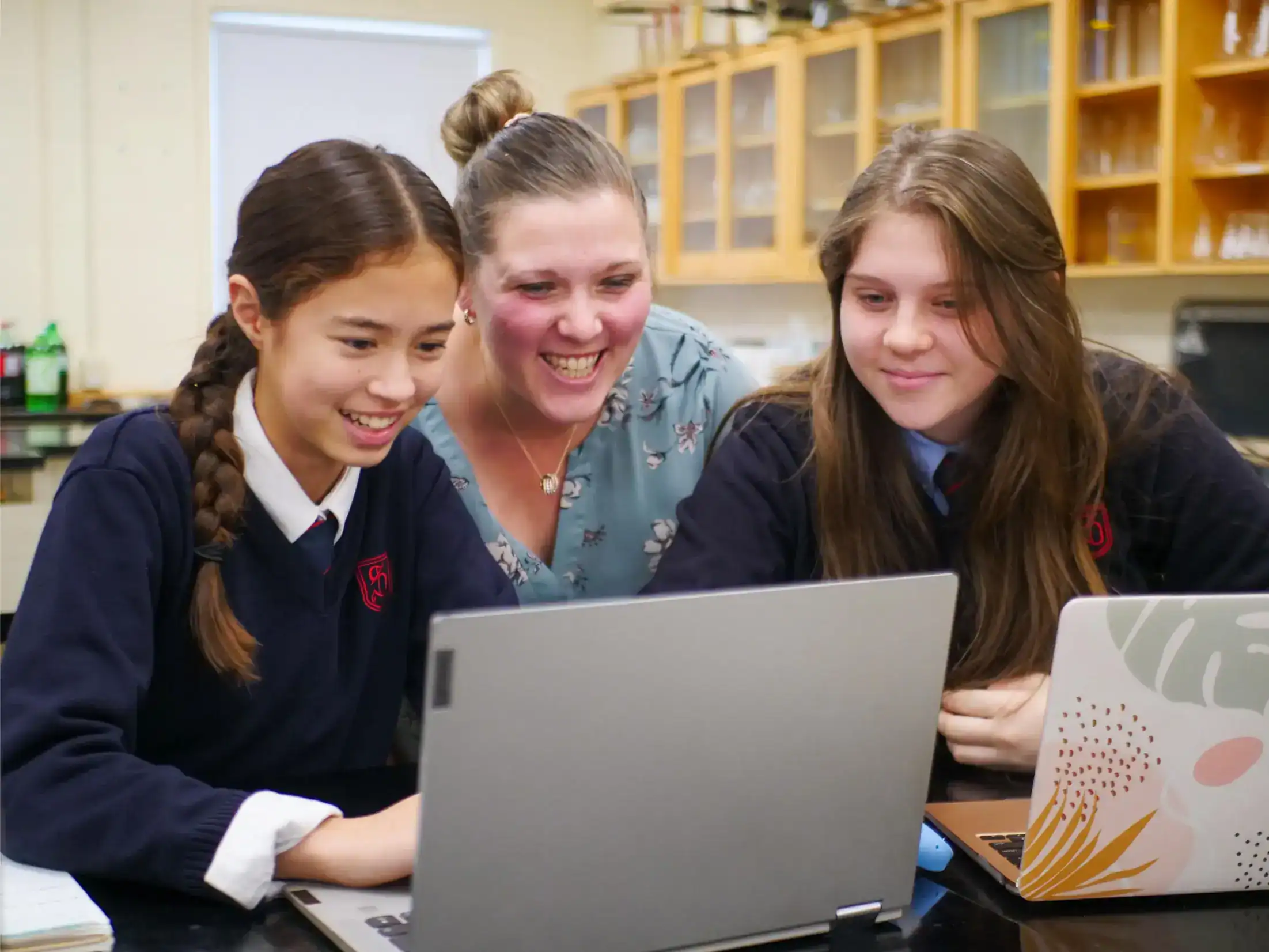 Engaging students and teacher collaborating on laptops in a classroom setting.