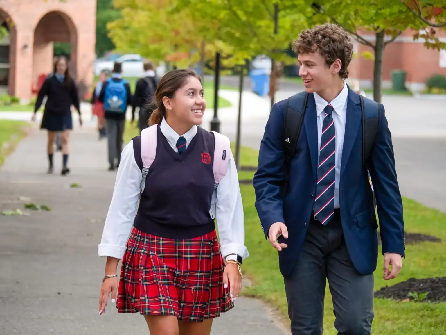 Smiling students in school uniforms walking outdoors, enjoying their school day at an international school.