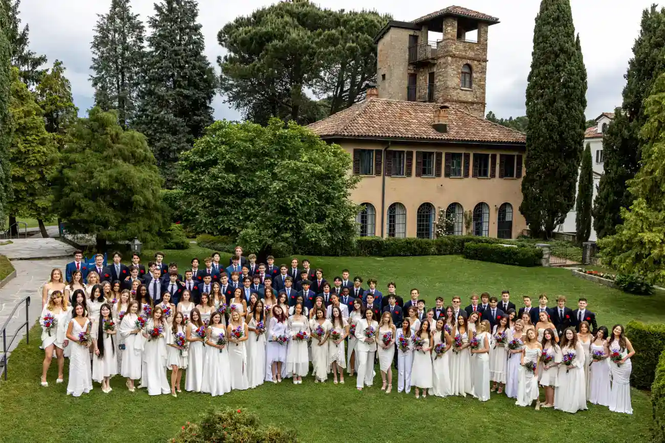 This Year at TASIS: 2023 21 Gradudates of a prestigious international school celebrating graduation ceremony in a lush green outdoor setting.