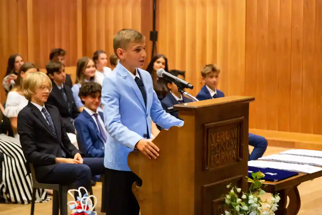 This Year at TASIS: 2023 22 Young student giving speech at academic event in a classroom setting.