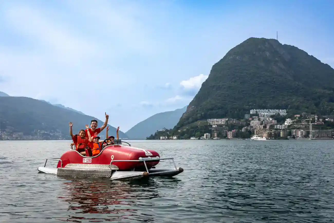 This Year at TASIS: 2023 29 Kids enjoying a boat ride on a scenic lake near mountain ranges.