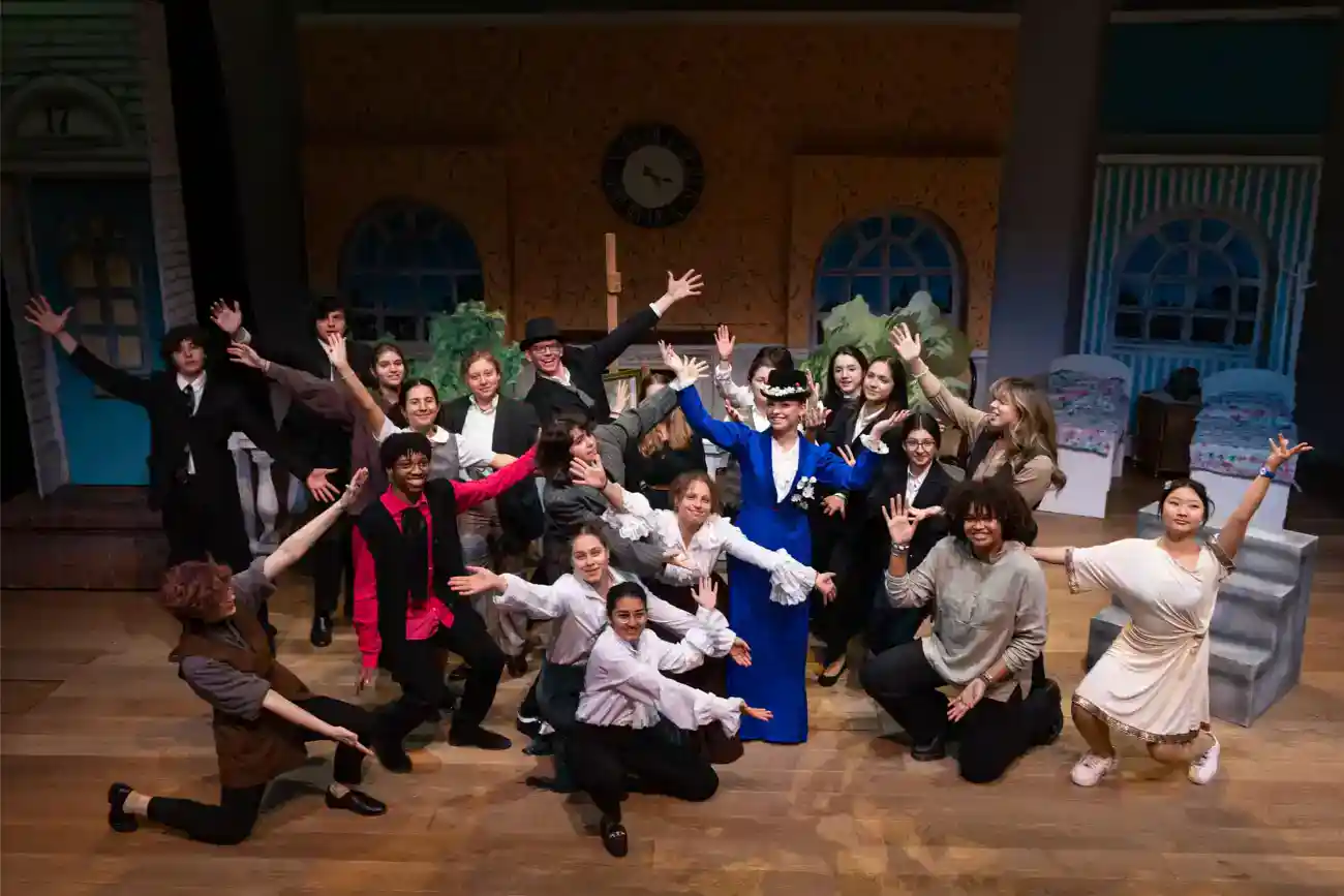 This Year at TASIS: 2023 8 Diverse group of students performing on stage in a theater atmosphere at World Schools event.