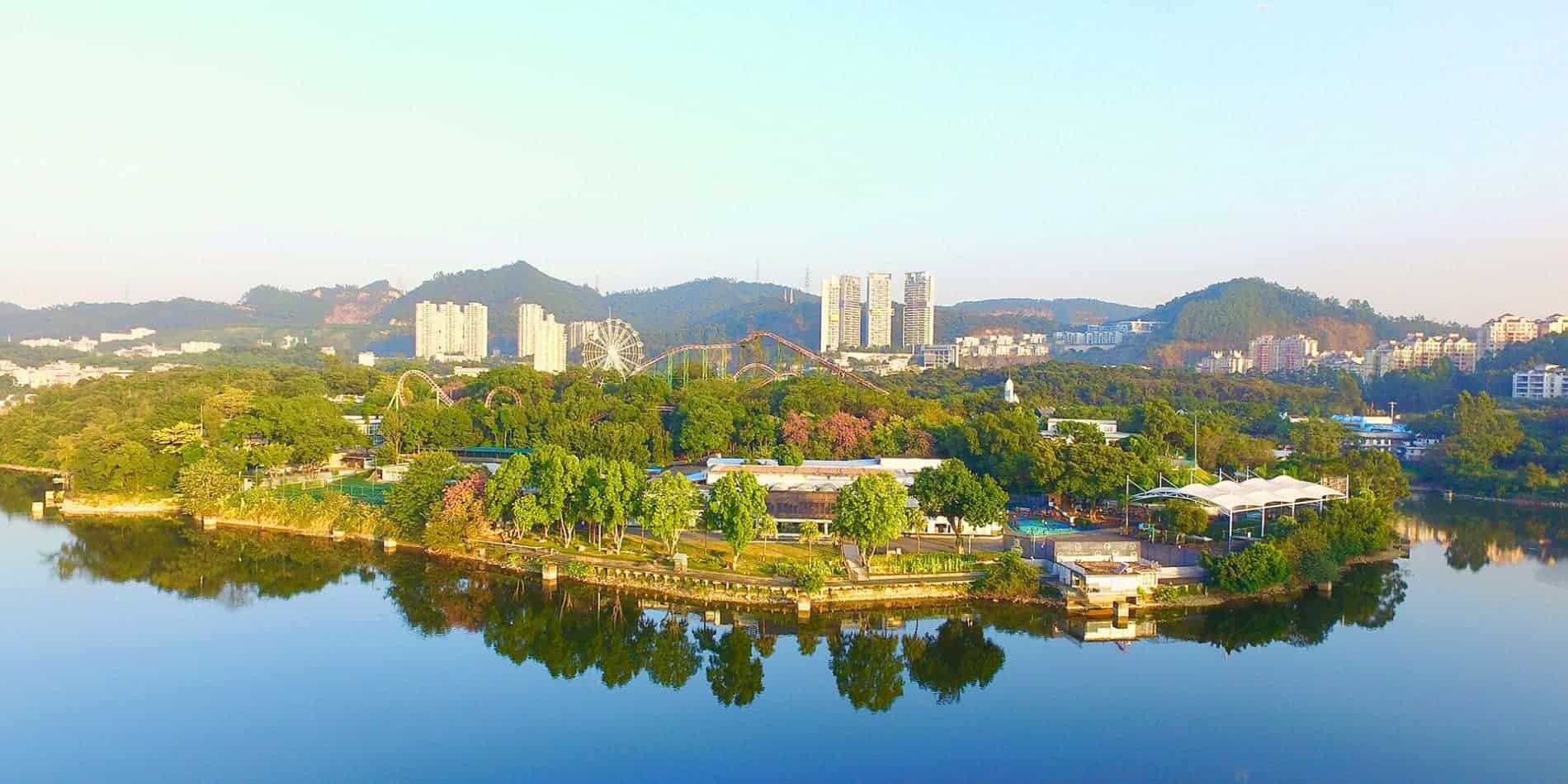 学校4 Serene lakeside view of a prominent world school surrounded by lush greenery and modern city buildings.